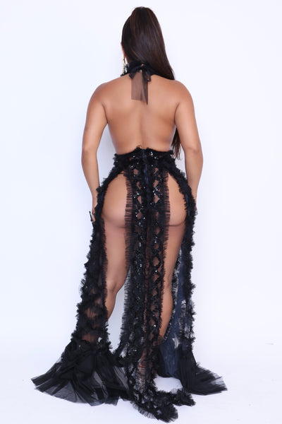 Black gown back view with exposed back and sheer sequin ruffle trail down to the floor.