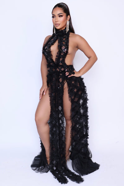 Side pose of black gown with open slit and sequined ruffles cascading from hip to hem.