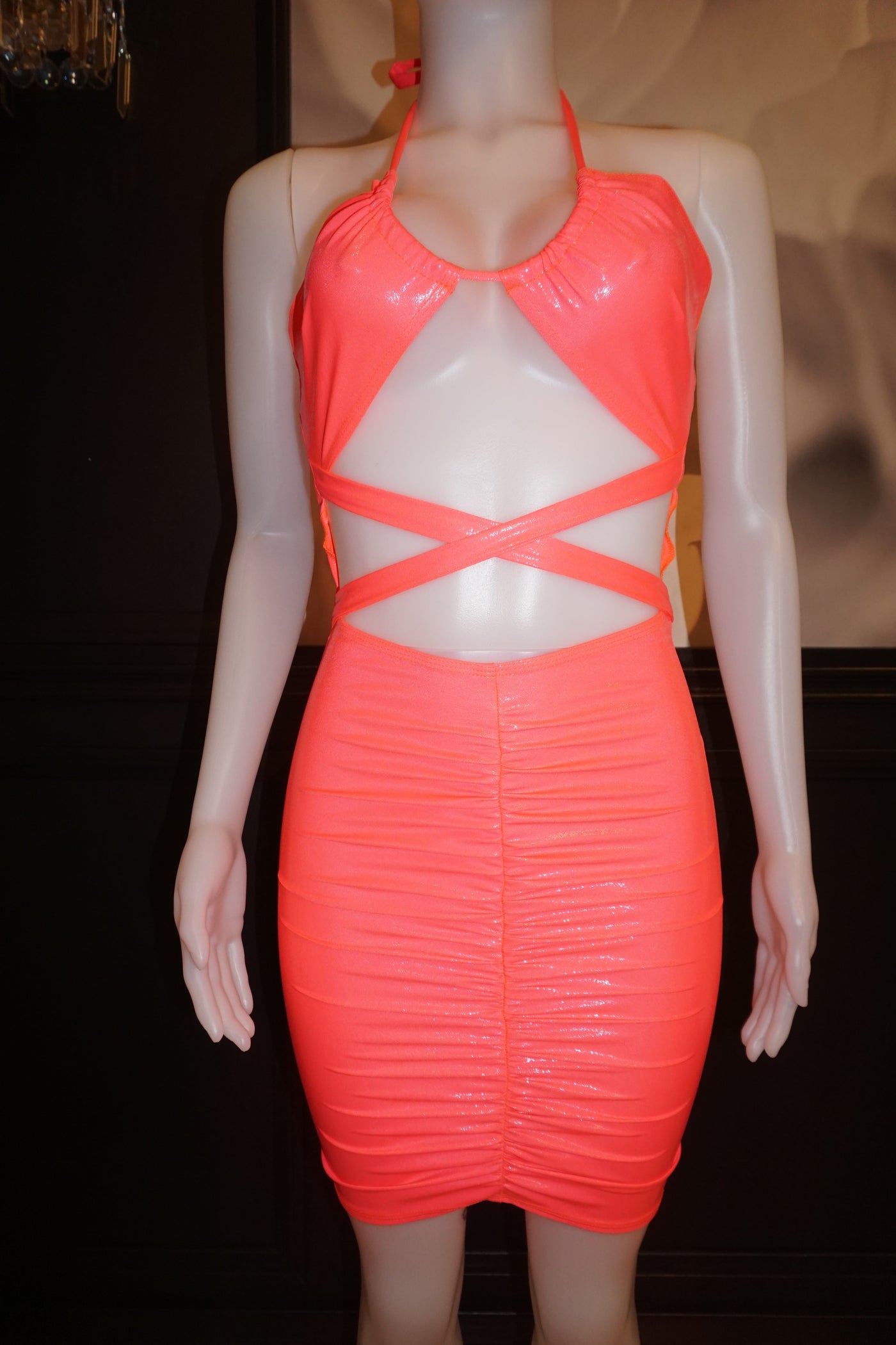 Pink mid-thigh halter dress with open upper torso and underbust cutouts, featuring scrunched detailing on the front lower half and a body-hugging fit.